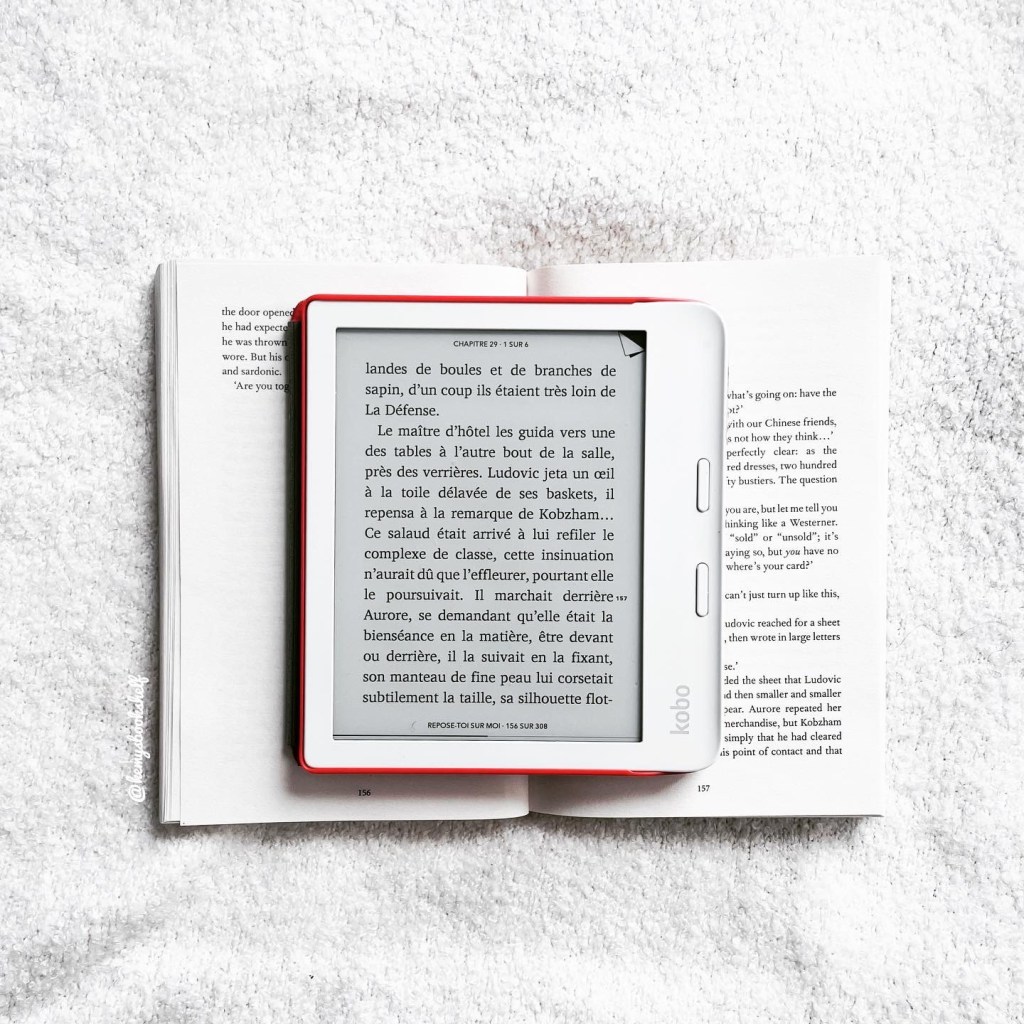flat-lay of an open paperback of Lean on me with an open Kobo e-readeron it. The Kobo displays a folded back. The background is a white wool surface